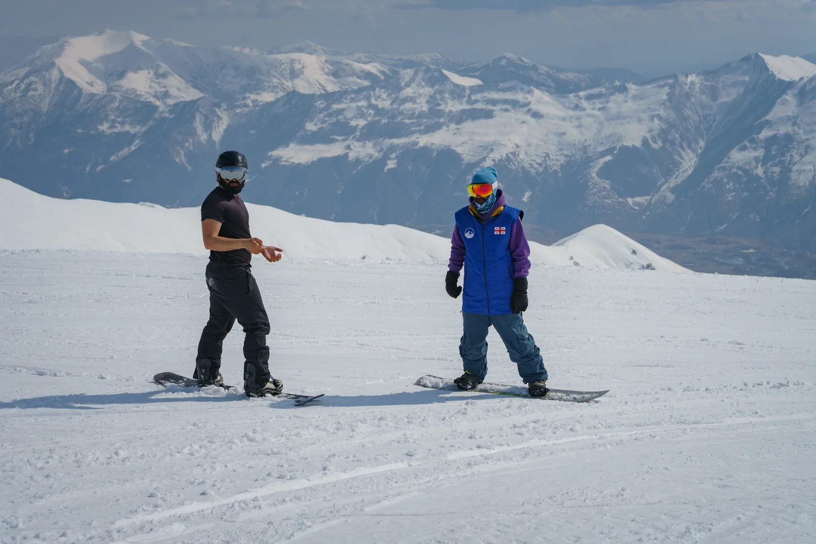 Instructor riding alongside a student on the open piste at Gudauri